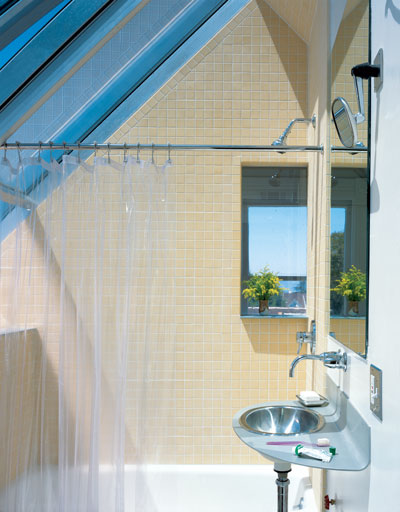 
A window and a deep skylight amplify the sense of space in a small bathroom. Aluminum was bent into sleek, curved sinks throughout the project. Karl uses an old Volvo mirror for shaving.
